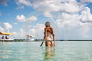 Woman in bikini bathing suit in blue water at the Laguna Bacalar, Chetumal, Quintana Roo, Mexico.