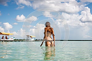 Woman in bikini bathing suit in blue water at the Laguna Bacalar, Chetumal, Quintana Roo, Mexico.