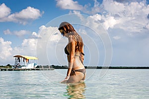 Woman in bikini bathing suit in blue water at the Laguna Bacalar, Chetumal, Quintana Roo, Mexico.