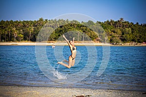 Woman in bikini on the beach jumping under water