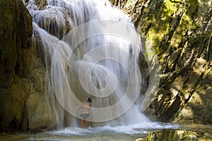 Woman with bikini black play water at Erawan Waterfall