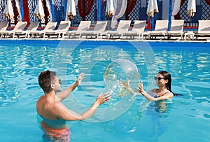 Woman in bikini and her boyfriend playing with inflatable ball at resort