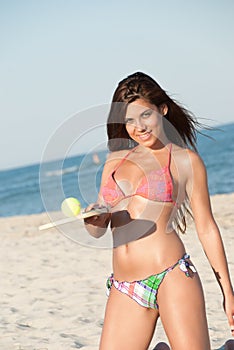 Woman in bikini holding a beach racket