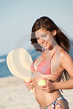 Woman in bikini holding a beach racket