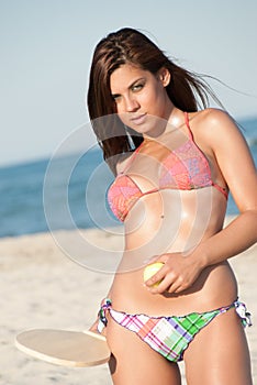 Woman in bikini holding a beach racket