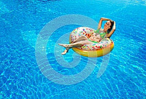 Woman in bikini on the inflatable mattress in the swimming pool.