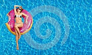 Woman in bikini on the inflatable mattress in the swimming pool.