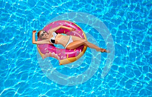 Woman in bikini on the inflatable mattress in the swimming pool.