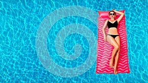 Woman in bikini on the inflatable mattress in the swimming pool.