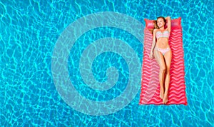 Woman in bikini on the inflatable mattress in the swimming pool.