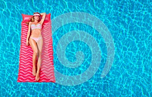 Woman in bikini on the inflatable mattress in the swimming pool.