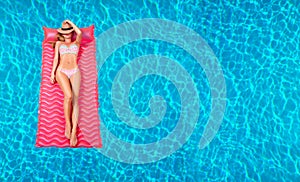 Woman in bikini on the inflatable mattress in the swimming pool.