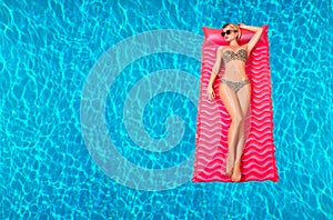 Woman in bikini on the inflatable mattress in the swimming pool.