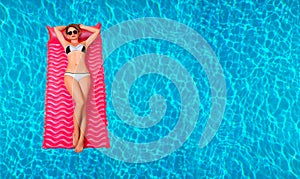 Woman in bikini on the inflatable mattress in the swimming pool.