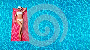Woman in bikini on the inflatable mattress in the swimming pool.