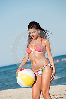 Woman in bikini joying with colorful beach ball
