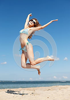 Woman in bikini jumping on the beach