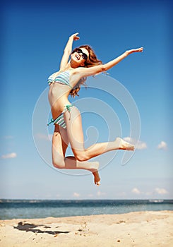 Woman in bikini jumping on the beach