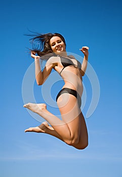 Woman in bikini jumping high