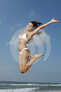 Woman In Bikini Jumping Midair On Beach photo