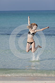 Woman with bikini jumping in the sea hochformat