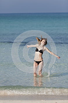 Woman with bikini jumping in the sea hochformat