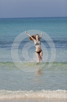 Woman with bikini jumping in the sea hochformat