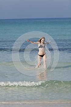 Woman with bikini jumping in the sea hochformat