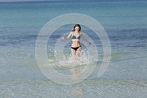 Woman with bikini jumping in the sea hochformat