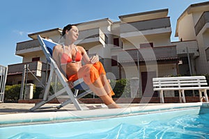 Woman in bikini and pareo sitting on beach chair