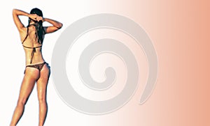 Woman in bikini pulling her hair up with reserved background. photo