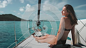 Woman in bikini relaxes sitting on yacht deck