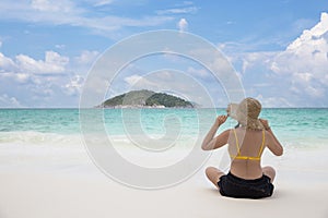 Woman bikini relaxing from behind wearing sun straw hat on beach looking at ocean in a tropical , Summer holiday travel concept