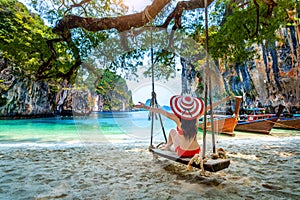 Woman in bikini relaxing on swing at Ko lao lading island, Krabi, Thailand