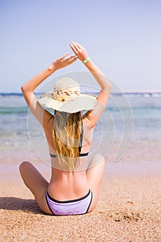 Woman in bikini resting on the beach in straw hat. Summer vocation