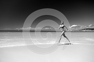 Woman in bikini running on sea beach