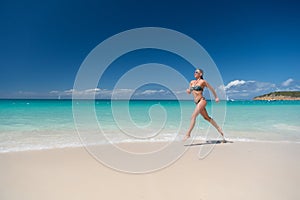 Woman in bikini running on sea beach