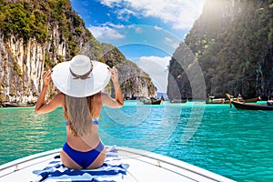 A woman in bikini sitting on a boat and looking at the lagoon at Phi Phi islands