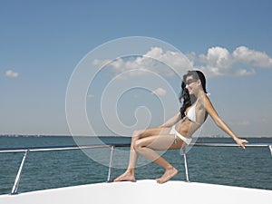 Woman In Bikini Sitting On Railing Of Yacht