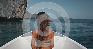 Woman in bikini on speed boat, sea rock landscape