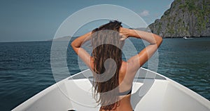 Woman in bikini on speed boat, sea rock landscape