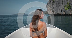 Woman in bikini on speed boat, sea rock landscape