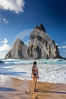 Woman in bikini stands near the big rock Fernando de Noronha, isle in the Northeast of Brazil photo