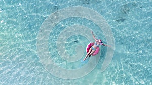 woman in bikini sunbathing as laying on swim ring as blue sea water in background