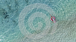 woman in bikini sunbathing as laying on swim ring as blue sea water in background