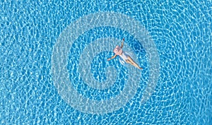 Woman in bikini sunbathing as laying on swim ring as blue sea water in background