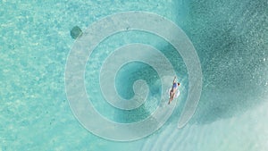 Woman in bikini sunbathing as laying on swim ring as blue sea water in Maldives
