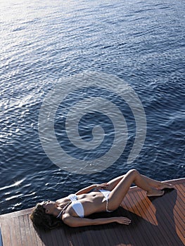 Woman In Bikini Sunbathing On Yacht's Floorboard