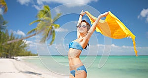 Woman in bikini and sunglasses over tropical beach