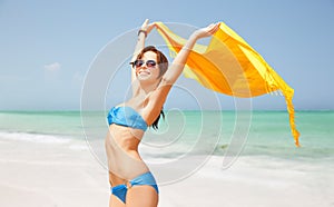 Woman in bikini and sunglasses with pareo on beach